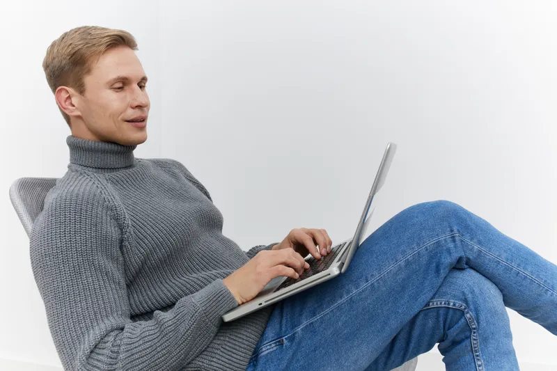 relaxed man using laptop casual wear sitting modern chair digital nomad remote work technology concept