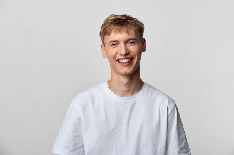 Smiling man in a white t shirt, casual style, friendly vibe and clean look, with natural light in a minimal studio setup for lifestyle or corporate use