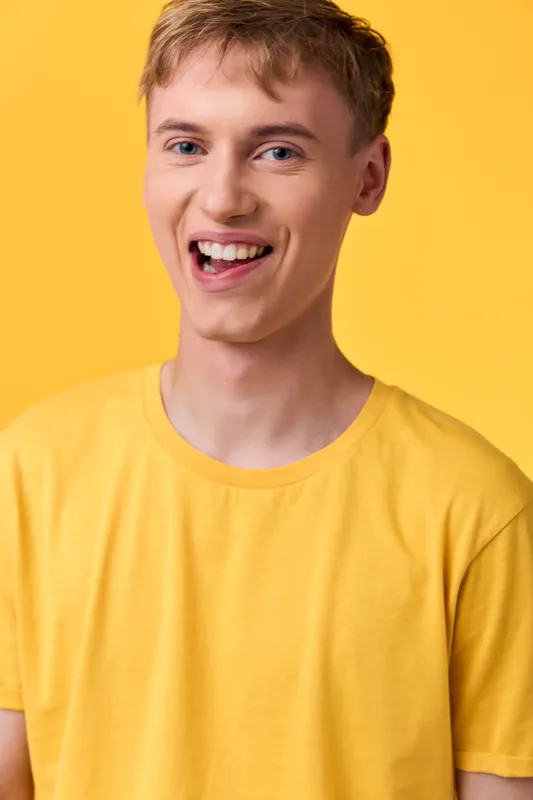 Smiling man in a bright yellow shirt against a yellow background, conveying cheerful energy and confident vibe, suitable for lifestyle, fashion or advertising visuals