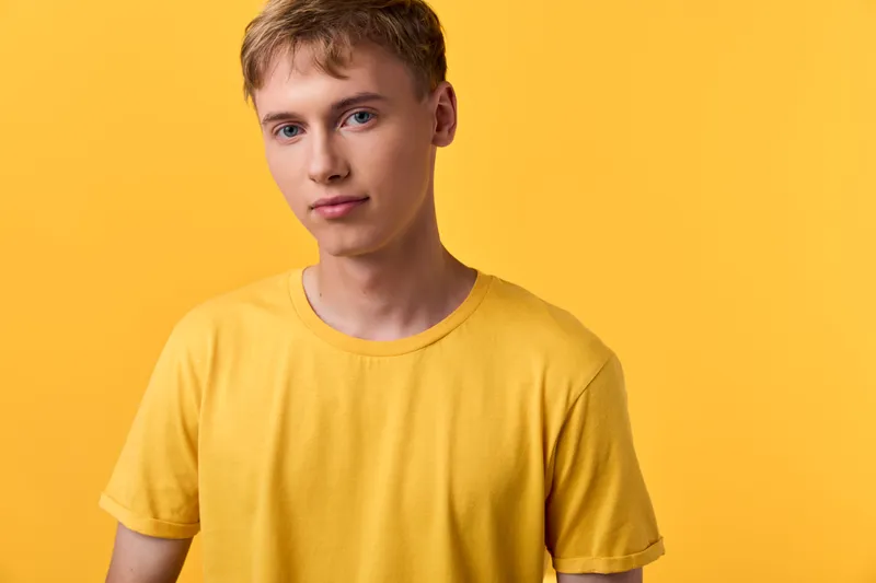 Young man in a yellow tee against a bright yellow background, casual studio shot with clean lighting, relaxed expression, simple composition for lifestyle and fashion stock use