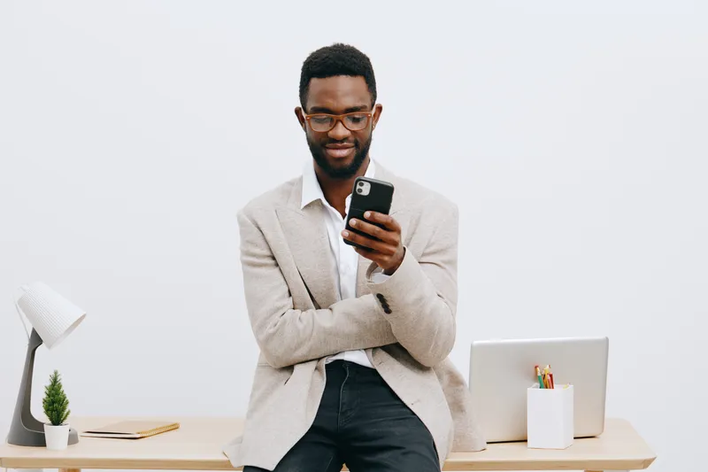 Smiling man using smartphone in modern office, casual business attire, indoor workspace, technology and communication concept, cheerful and confident expression, professional environment, male adult, 