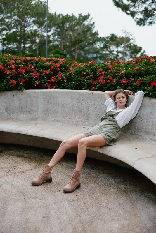 Young female model in casual summer outfit relaxing in a park surrounded by vibrant flowers, conveying a feeling of joy and tranquility