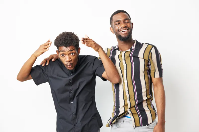 Two joyful African American men having fun together, showcasing friendship and happiness in a bright and lively atmosphere. Perfect for promoting positive relationships.