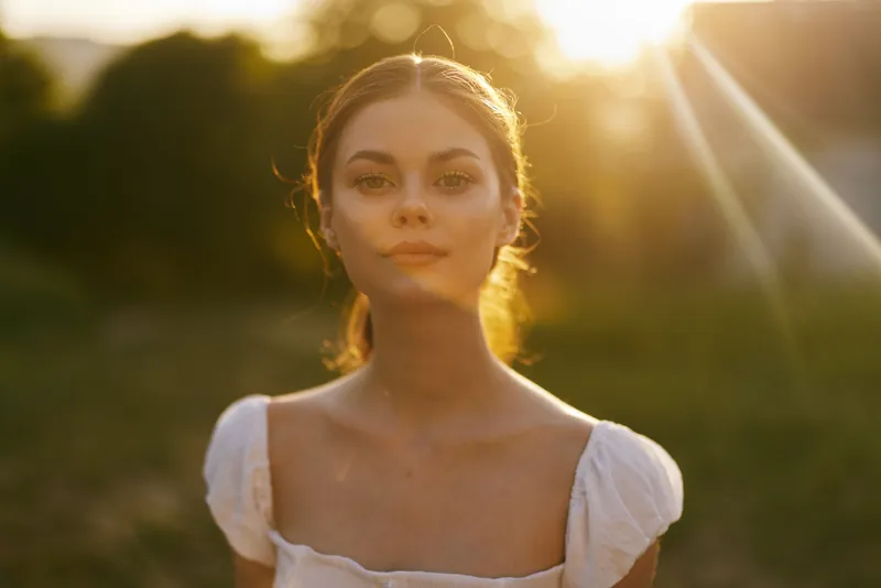 Serene young woman in a white dress at sunset, exuding calmness and beauty in nature, perfect for seasonal and emotional themes