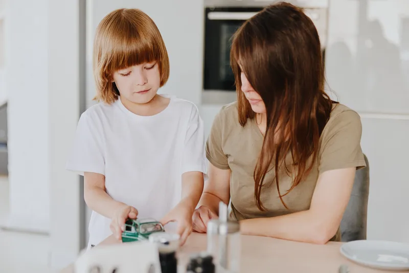 Caring woman and child enjoying quality time together while exploring technology, showcasing the bond between parent and child in a modern home setting.