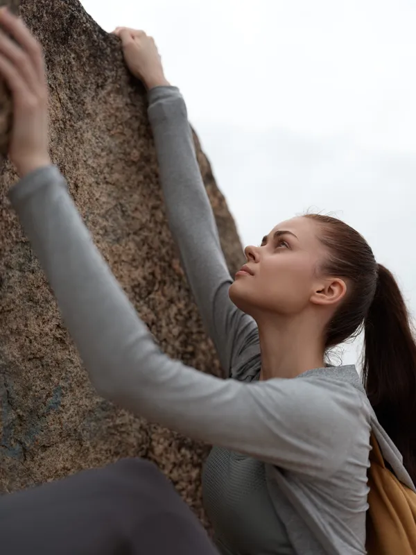 A young athletic woman climbing a rocky surface, showcasing determination and focus in outdoor adventure activities, perfect for sports and fitness themes