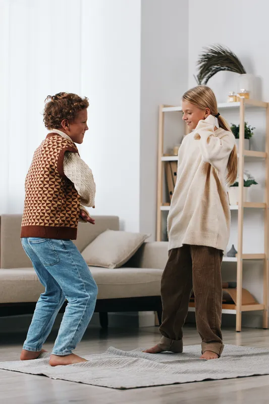 Authenticity shines in a cozy home moment as children engage in a playful school themed game, dancing in casual clothes, capturing a warm lifestyle scene.