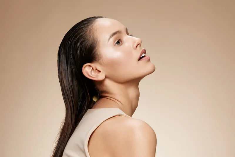 Elegant woman with straight hair in neutral dress, exuding confidence and beauty against a soft beige background, perfect for fashion and beauty themes