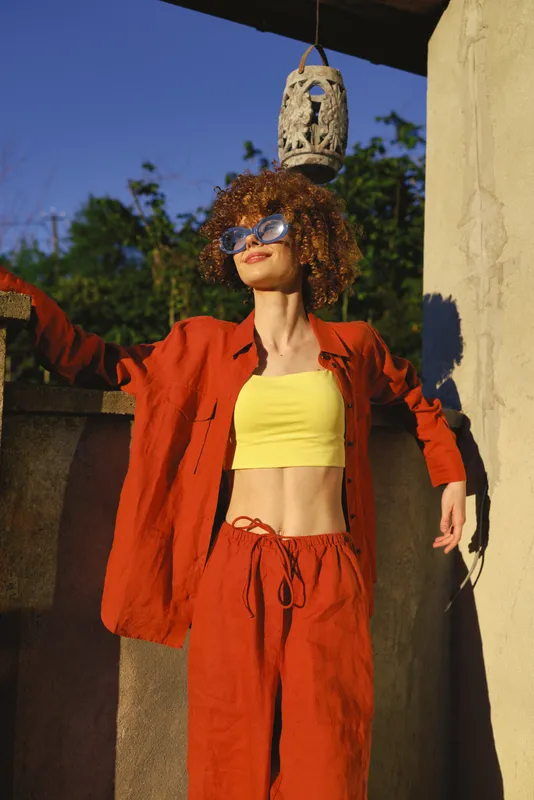 Woman lifestyle outdoors sunny fashion casual summer outfit orange sunglasses posing confidently in a bright outdoor setting with vibrant colors, relaxed mood, sunlit energy
