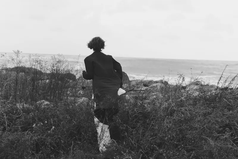 Runner, silhouette, coastal landscape and ocean view with shore and wind in motion, capturing movement across wild grass, evoking exploration, nature, and seaside serenity