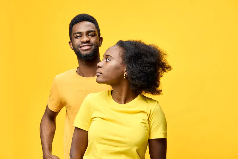 Smiling young African couple dressed in yellow t shirts against a vibrant yellow background, showcasing joy, happiness, and connection