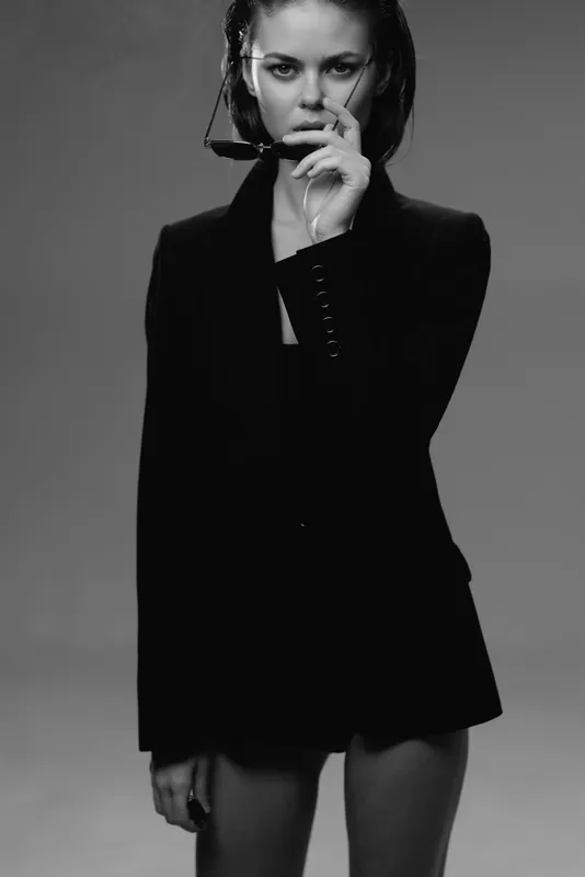 Black and white portrait of a young woman in a blazer with intense expression and minimalistic style