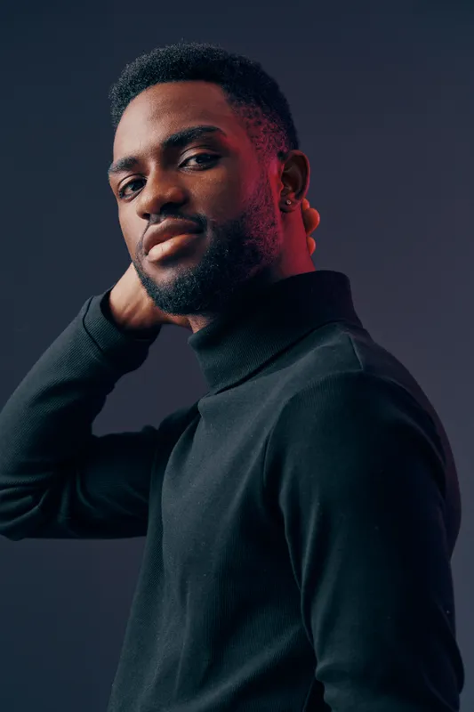 Confident young man in a black turtleneck, showcasing a modern style with a subtle smile against a dark gradient background, perfect for personal branding