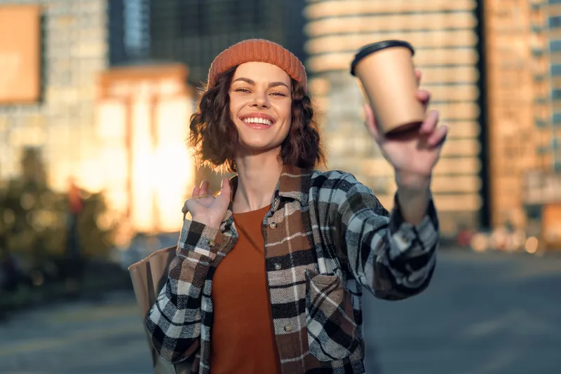woman coffee smile city candid golden young woman holding a takeaway cup, authenticity and mindful living in golden hour glow with emotional storytelling, urban vibe