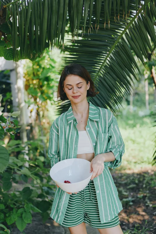 Woman, outdoor, garden, palm, leaves, greenery, sunny, smile, cheerful, fashion, blazer, striped, green, shorts, bowl, holding, presenting, candid, lifestyle, nature, portrait, beauty, relaxed,