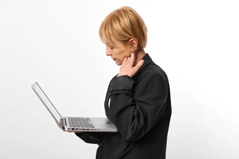 Woman business laptop in studio isolated setting, blond manager in black blazer, hand on ear, focused thinking pose, white background, professional work, moment