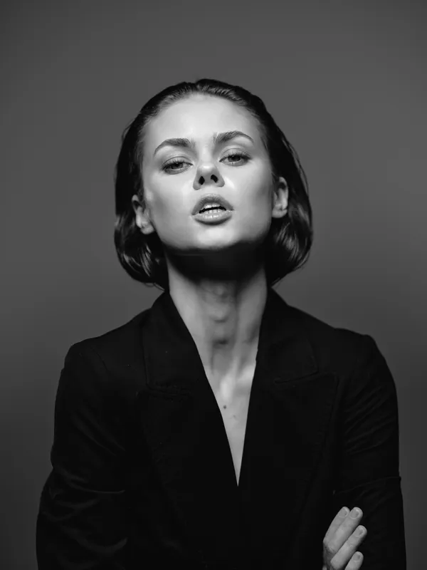 Black and white portrait of a young woman with short hair wearing a dark jacket with a confident expression.