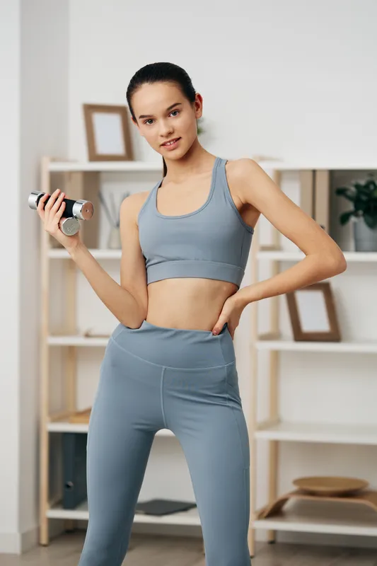 Fitness, woman, workout, dumbbell, home, athletic, sport, exercise, training, health, a focused woman lifts a dumbbell during a home workout in blue activewear, standing in a bright studio.