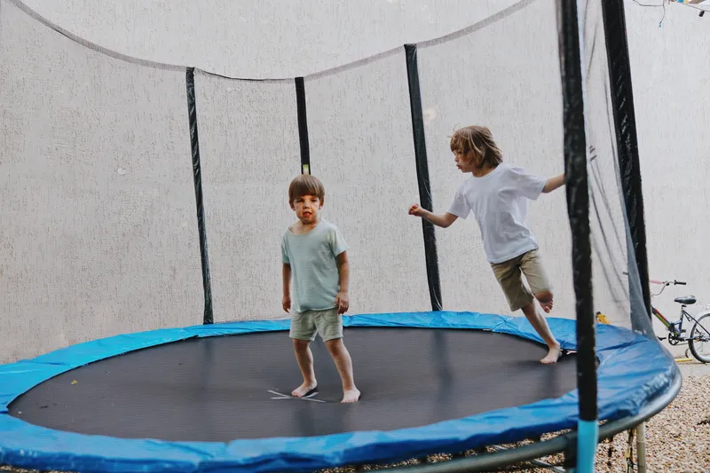 Two joyful boys bouncing on a trampoline, showcasing their playful nature and happiness. This engaging scene captures the essence of childhood fun and energy.