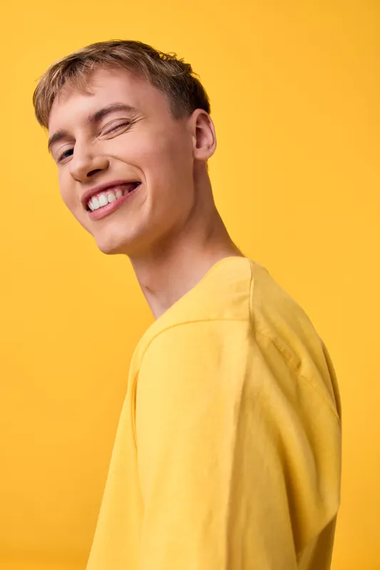 Smile, man in yellow shirt against a bright yellow backdrop exudes cheerful energy, casual lifestyle scene capturing optimism and positive mood in contemporary photography