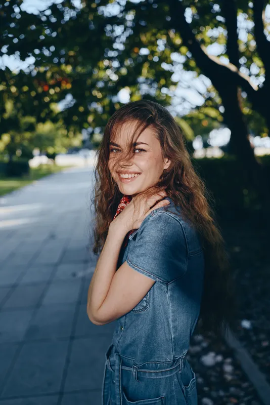 smiling woman in modern boho-western denim street style, film color with natural sunlight and casual outdoor background expressing happiness and free spirit