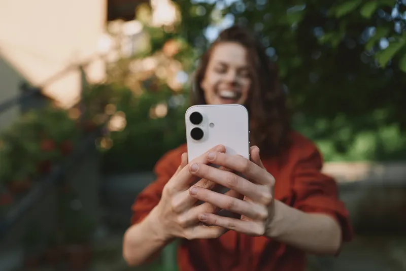 Smiling woman taking a selfie outdoors, casual lifestyle portrait, warm natural light, cheerful mood, self expression and everyday connection