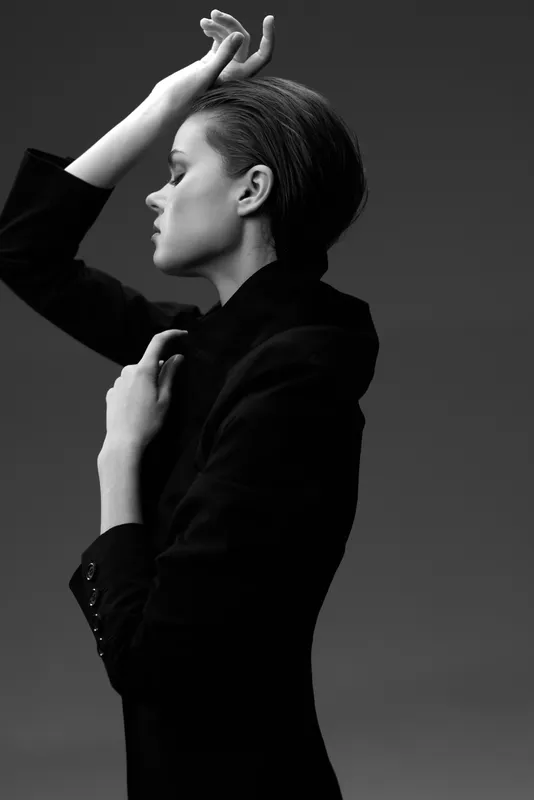 Black and white portrait of a woman in a suit with elegant pose and thoughtful expression