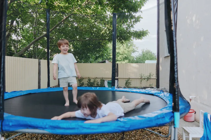 Two playful boys enjoying their time on a trampoline, showcasing joy, childhood innocence, and active play in a sunny outdoor setting.