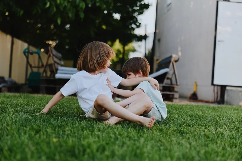 Joyful children playing outdoors in a sunny yard, enjoying their carefree moments on a beautiful day filled with laughter and friendship.