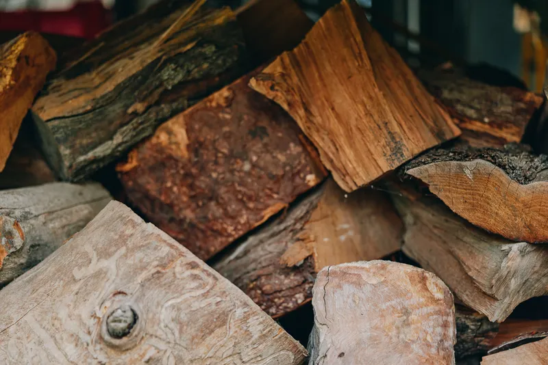 firewood stacked wood chopped logs dry wood bark texture woodpile for rustic cabin, middle-aged homeowner preparing winter, rough cut oak, cozy hearth fuel, outdoor rural storage