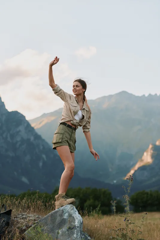 Young woman in casual clothes standing on a rock in a mountain landscape, enjoying nature and outdoor adventure. Concept of lifestyle, freedom, and exploration.