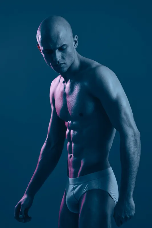 Muscular man in black and white lighting, exuding strength and determination with a focused expression, showcasing the beauty of the human physique.