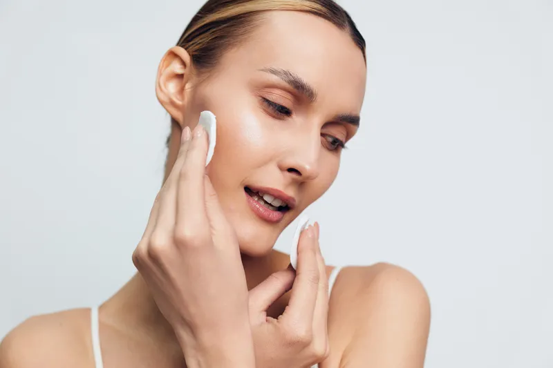 A close up of a woman applying a cotton pad to her cheek during a skincare routine, conveying calm, self care and smooth skin. Focus on facial care and daily beauty ritual.