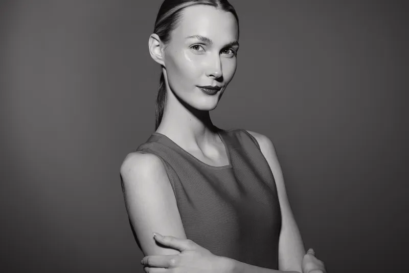 Portrait of a confident white woman with light skin and slicked back hair wearing sleeveless top. Studio lighting creates a strong and elegant mood. Concept for fashion and beauty.
