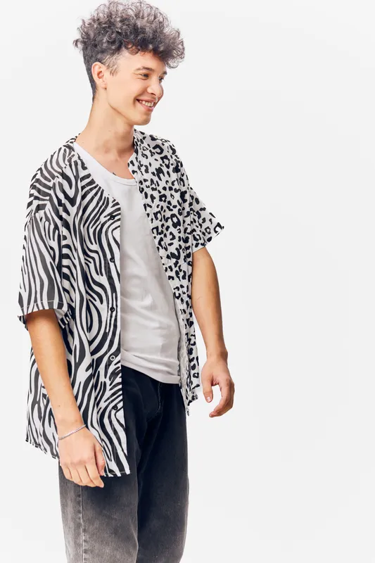 young man wearing animal print shirt smiling happily with casual style and curly hair on white background, modern fashion and natural expression