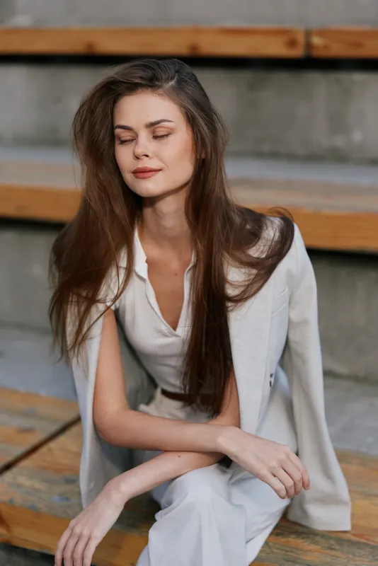 calm woman in white outfit sitting on wooden steps with closed eyes serene expression natural beauty calm woman white outfit steps