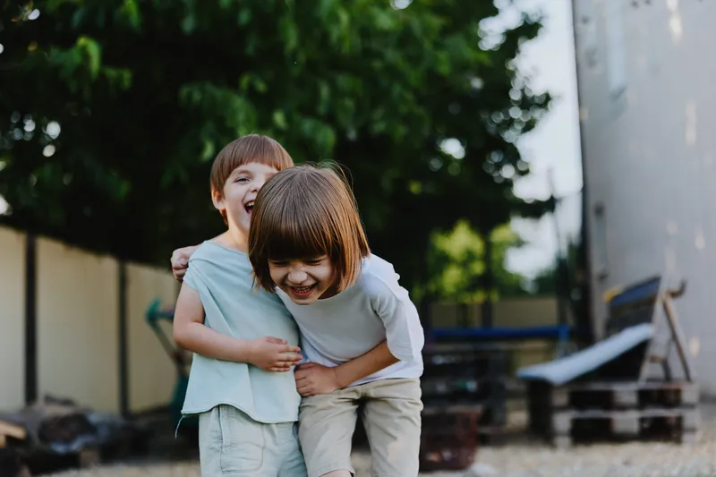 Happy children playing outdoors, laughing and enjoying their time together in a bright and vibrant environment, surrounded by greenery and natural light.