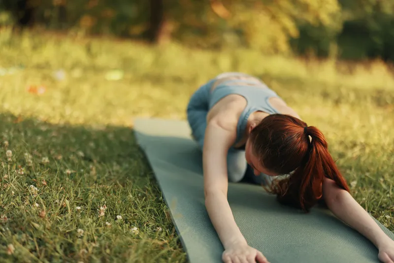 Young woman practicing yoga outdoors in a peaceful park setting, expressing tranquility and focus Soft green tones evoke a serene atmosphere for yoga enthusiasts