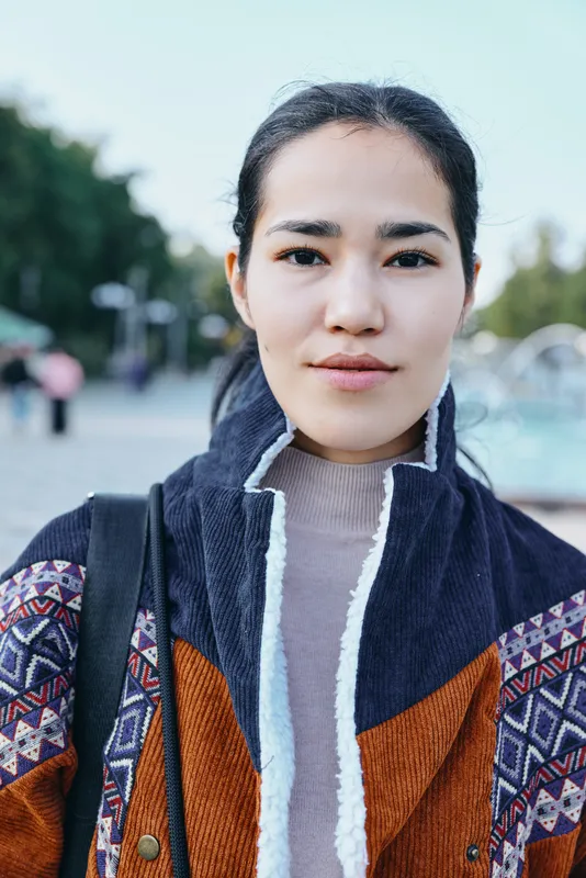 Woman outdoors wearing a patterned coat, streetwear inspired fashion, urban casual look with natural light, stylish atmosphere, everyday wardrobe, confident expression in a street setting