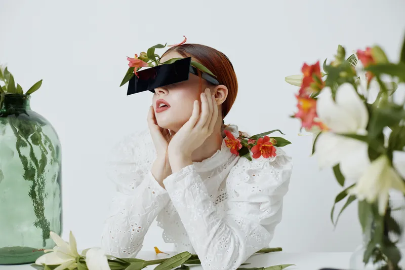 Fashionable young woman in modern eyewear among fresh flowers, embodying beauty and elegance with a touch of nature s charm