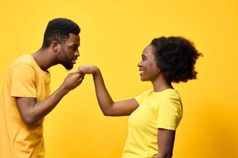 A joyful couple in yellow outfits gazing into each other s eyes, showcasing love and affection against a vibrant yellow background filled with warmth and positivity