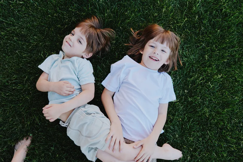 Happy children lying on green grass, enjoying a sunny day filled with laughter and joy. This playful scene captures the essence of childhood moments beautifully.