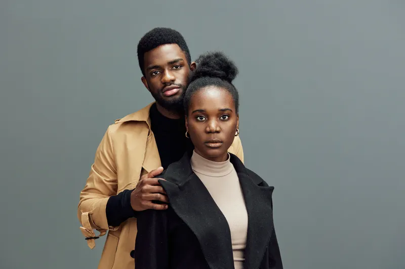 Elegant couple portrait on a muted gray background, showcasing stylish fashion, emotions of confidence, and modern aesthetics