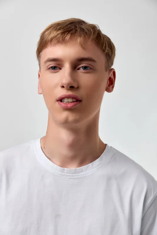 Young man in a white t shirt in a studio, relaxed expression, clean background, casual fashion, modern minimal vibe, approachable and fresh look for lifestyle scenes