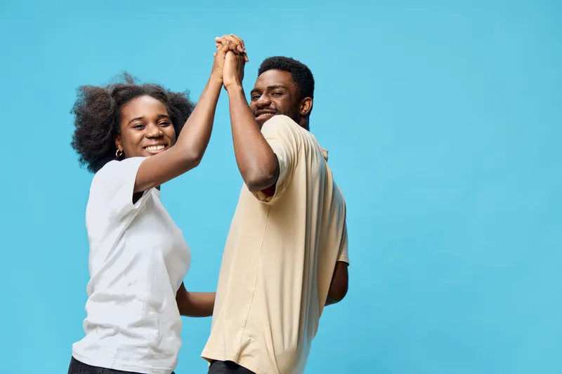 Happy couple dancing together against a blue background, expressing joy and love with vibrant emotions and casual summer attire