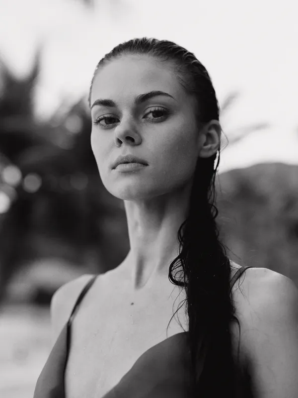 Black and white portrait of young woman with wet hair looking serious with blurred background and soft natural light