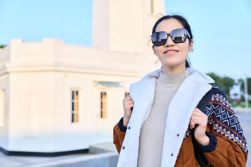 Fashion, woman in stylish coat and oversized sunglasses in outdoor urban setting, casual street style, neutral knitwear and shearling jacket, confident pose, modern vibe, daytime light