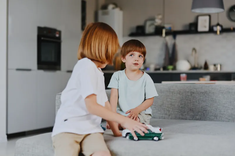 Two children playing together, focusing on their interaction and joy as they enjoy imaginative playtime in a bright, modern living room environment.