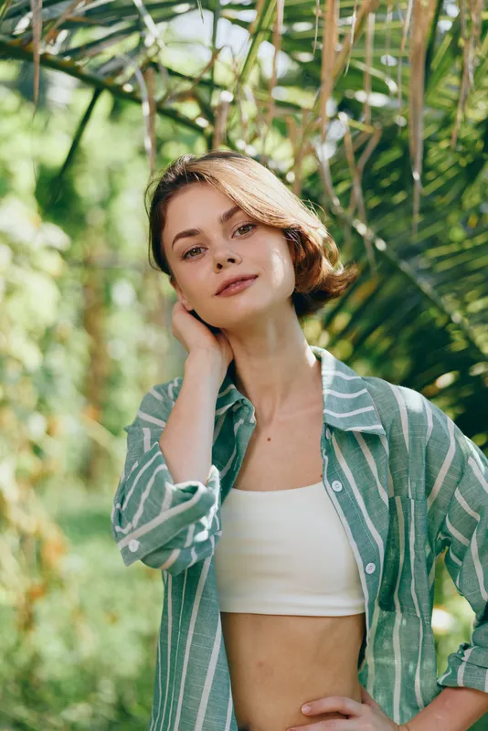 woman outdoors portrait in natural light, relaxed mood, green striped shirt, crop top, soft smile, sunlit garden backdrop, casual fashion, confident presence, carefree style