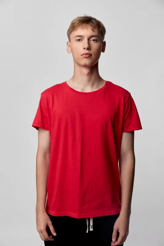 Red t shirt worn by a standing youth in a studio setting, casual fashion with a relaxed pose, front view and clean background, everyday wardrobe concept